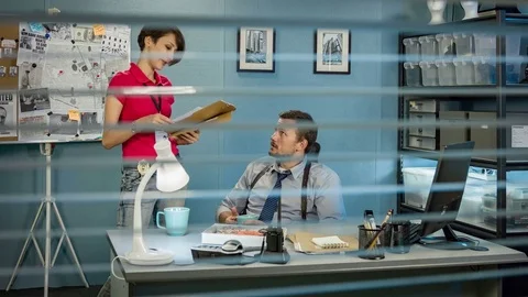 Detectives working in the office, view through the window blinds. Video stock 70520177