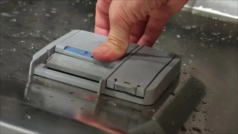 Detergent tablet is placed into the dishwasher compartment by a housekeeper Vidéo 307496118