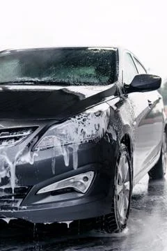 Detergent is washed off the front of a gray car with water Stock Photos