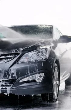 Detergent is washed off the front of a gray car with water Stock Photos