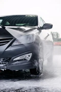 Detergent is washed off the front of a gray car with water Stock Photos