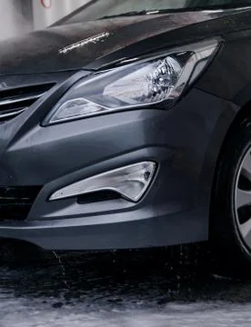 Detergent is washed off with a headlight of a gray car at a sink with water Stock Photos