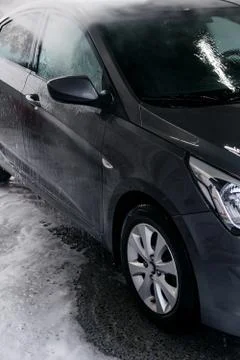Detergent is washed off with water from the side of the gray car at the sink Stock Photos
