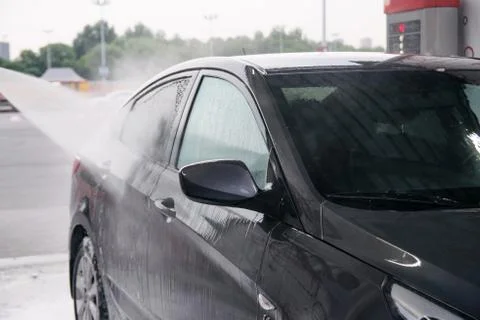 Detergent is washed off with water from the side of the gray car at the sink Stock Photos