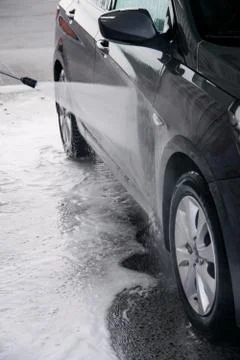 Detergent is washed off with water from the side of the gray car at the sink Stock Photos