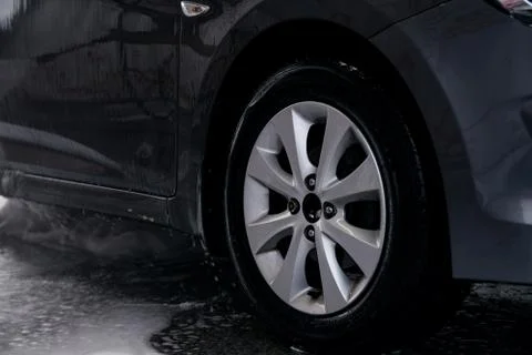 Detergent is washed off with water from the side of the gray car at the sink Stock Photos