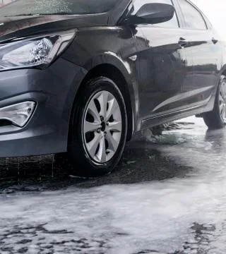 Detergent is washed off with water from the side of the gray car at the sink Stock Photos