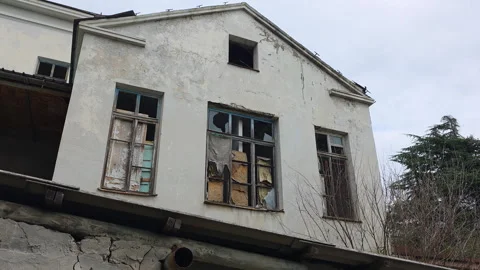 Deteriorating facade of an abandoned building with broken windows, revealing the Vídeo Stock 329743203