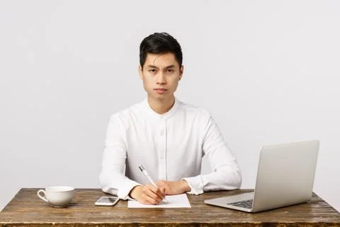 Determined and assertive, hardworking young asian businessman in office, sit Stock Photos