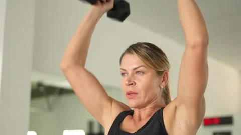 Determined athletic woman performing shoulder press exercise Stock Footage 329925565