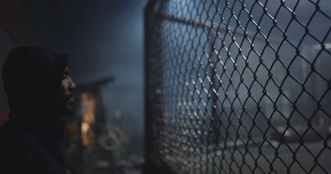 Determined boxer looking at boxing area through mesh fence Video stock 108548584