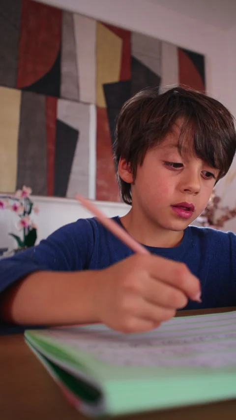 Determined child works through a written homeschool assignment at the dinin.. Vídeos de archivo 343652702