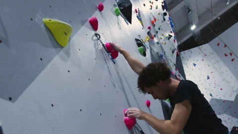 Determined Climber Skillfully Navigating Colorful Indoor Climbing Wall with Stock Footage 276969063
