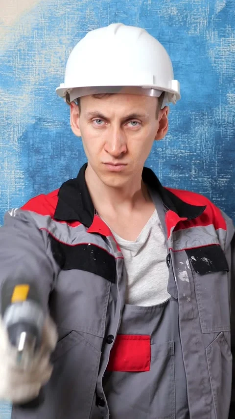 Determined construction worker with a serious expression pointing a cordless 库存影片 342906466