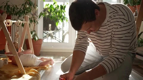 Determined father multitasking, assembling furniture with a screwdriver while Vídeos de archivo 344849143