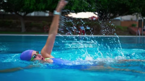 Determined female swimmer performing the backstroke in a clear blue pool. A.. Vídeos de archivo 345153235
