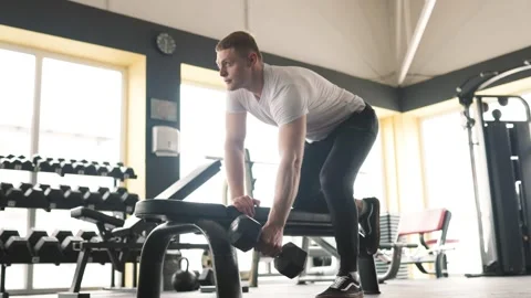 Determined guy engaged in a challenging weightlifting exercise, demonstrating Stock Footage 241415273