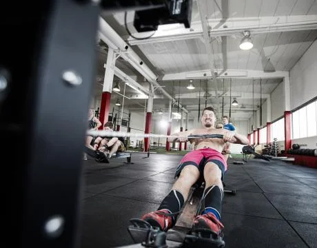 Determined Male Pulling Rowing Machine's Handle Фото