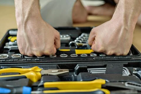 Determined man chooses tool from a case for work. Close up Stock Photos