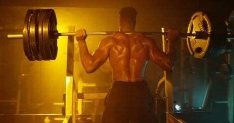 Determined man doing squat exercise with barbell in gym Stock Footage 116359718