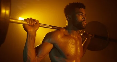 Determined man doing squat exercise with barbell in gym Stock Footage 116360679