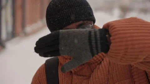 Determined man endures winter weather on city sidewalk. Urban resident in orange Stock Footage 335306058