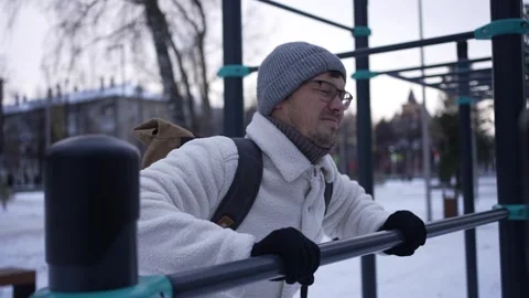Determined man performing dips on parallel bars in snowy park Stock-Footage 303831893