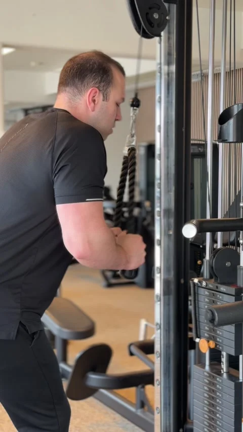 Determined man performing triceps pushdown on cable crossover machine Stock-Footage 336272007