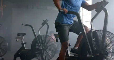 Determined man training hard on elliptical bike at gym, slow motion Stock Footage 335624136