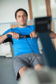 Determined man working out on row machine Photos