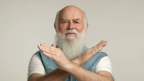 Determined Senior with Beard in Denim Vest Gives Strong 'No' Sign with Arms Stock Footage 261017947