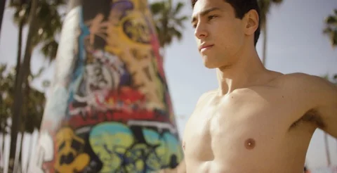 Determined shirtless man doing stretching exercise on a sunny day Stock Footage 106194236