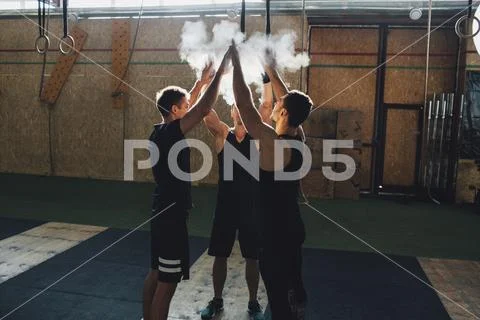 Determined Sportsmen Dusting Sports Chalk Together At Gym