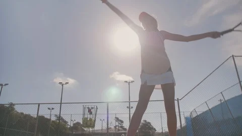 Determined tennis player serving on hard court with sun flare Stock Footage 93319508