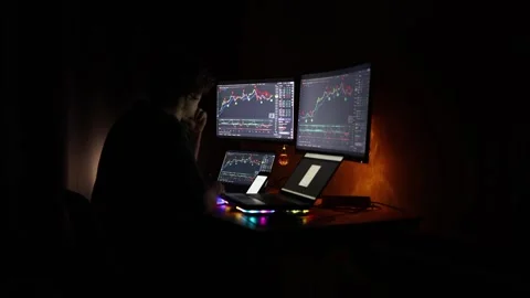 A determined trader in a calm, dimly lit room focuses on stock market charts dis Stock Footage 297111234