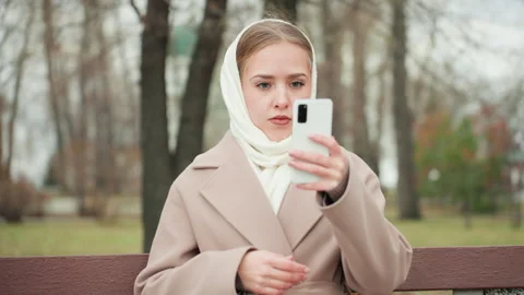 Determined woman confronts online attack in chilly park setting. Unfazed woman Stock Footage 332619836