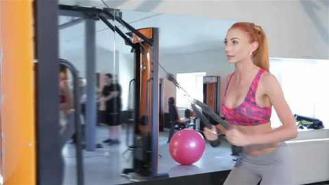 Determined woman pulling gym machine rope to strengthen her thighs Stock Footage 311545450
