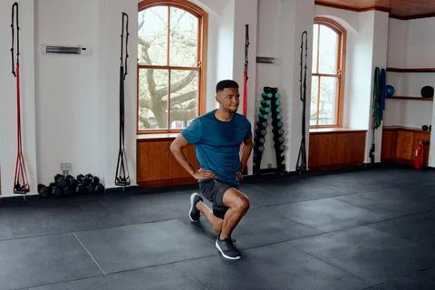 Determined young black man doing lunges with hands on hips at the gym Stock Photos