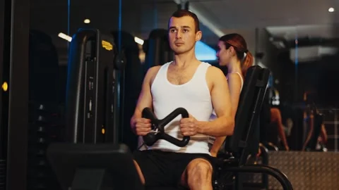 Determined young guy training his arms pulling handle of cable exercise machine Video stock 279958017