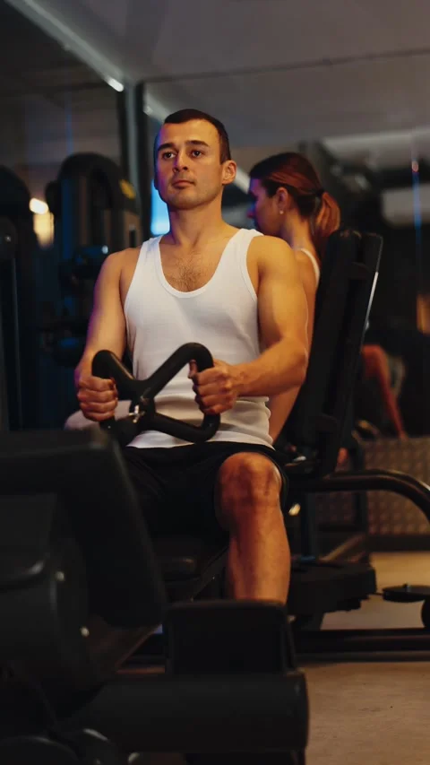 Determined young guy training his arms pulling handle of cable exercise machine Video stock 306975330