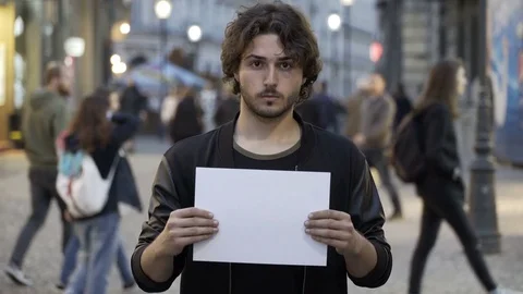 Determined young man holding a blank paper banner on the street with copy spa Vídeos de archivo 78120327