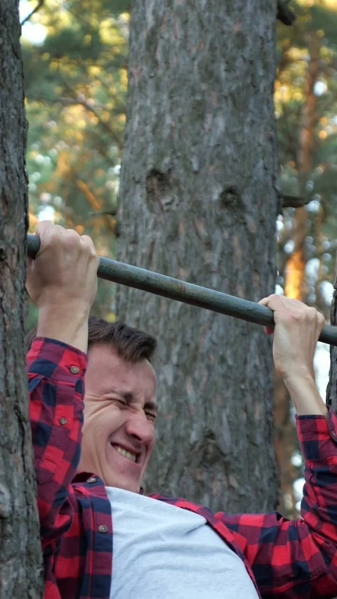 Determined young man performing difficult pull ups on a makeshift bar between Stock Footage 341677810