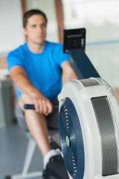 Determined young man working out on row machine Stock Photos