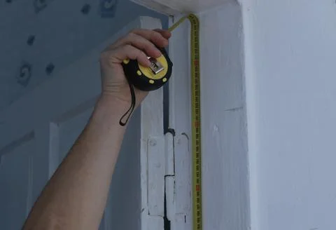 Determining the size of the doorway using a hand-held tape measure Stock Photos