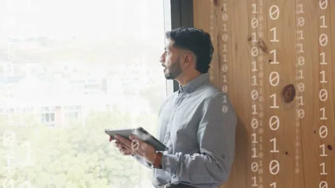 Dev leaning by window tapping tablet and visualizing network data as binary Stock Footage 333925458