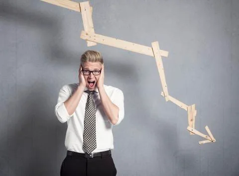 Devastated businessman shouting in front of graph pointing down. Stock Photos
