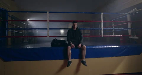 Devastated male boxer resting on empty boxing ring thinking of failure during 库存影片 150062688