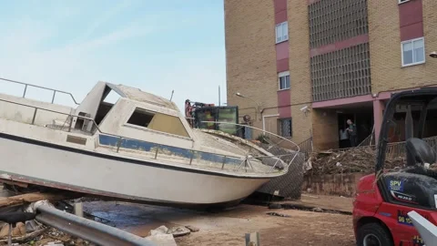 Devastating consequences of flooding, boat stranded near building in Valencia Stock Footage 292439877