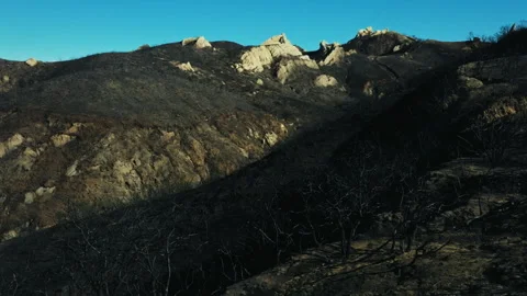 Devastating wildfire aftermath on a charred mountain landscape 스톡 동영상 332962176