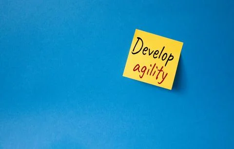 Develop agility symbol. Orange steaky note with concept words Develop Agili.. Stockfoto's
